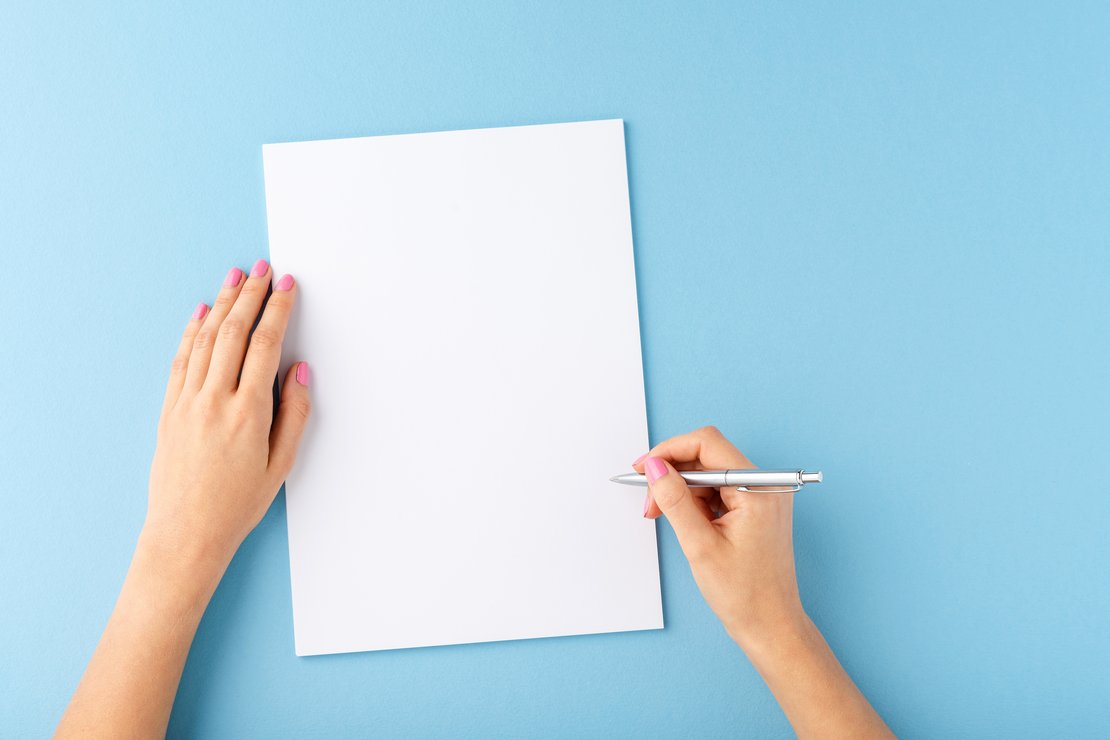 Zwei Hände an einem Blatt Papier, eine Hand hält einen Stift