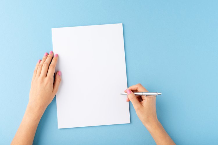 Zwei Hände, eine hält einen Stift die andere ein Blatt Papier